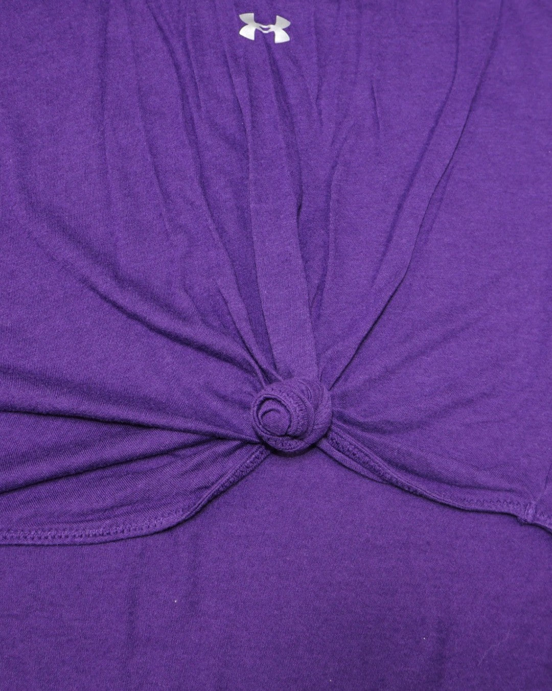 Detalle de nudo y logo Under Armour en espalda de top morado en The Reset