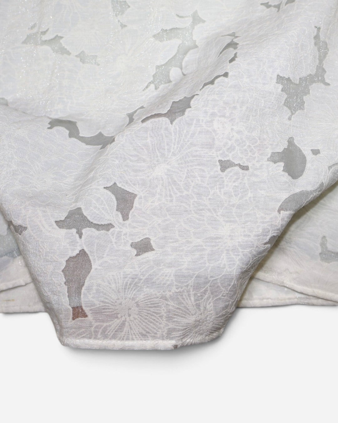 Detalle de tela floral con partes transparentes de blusa crema en The Reset