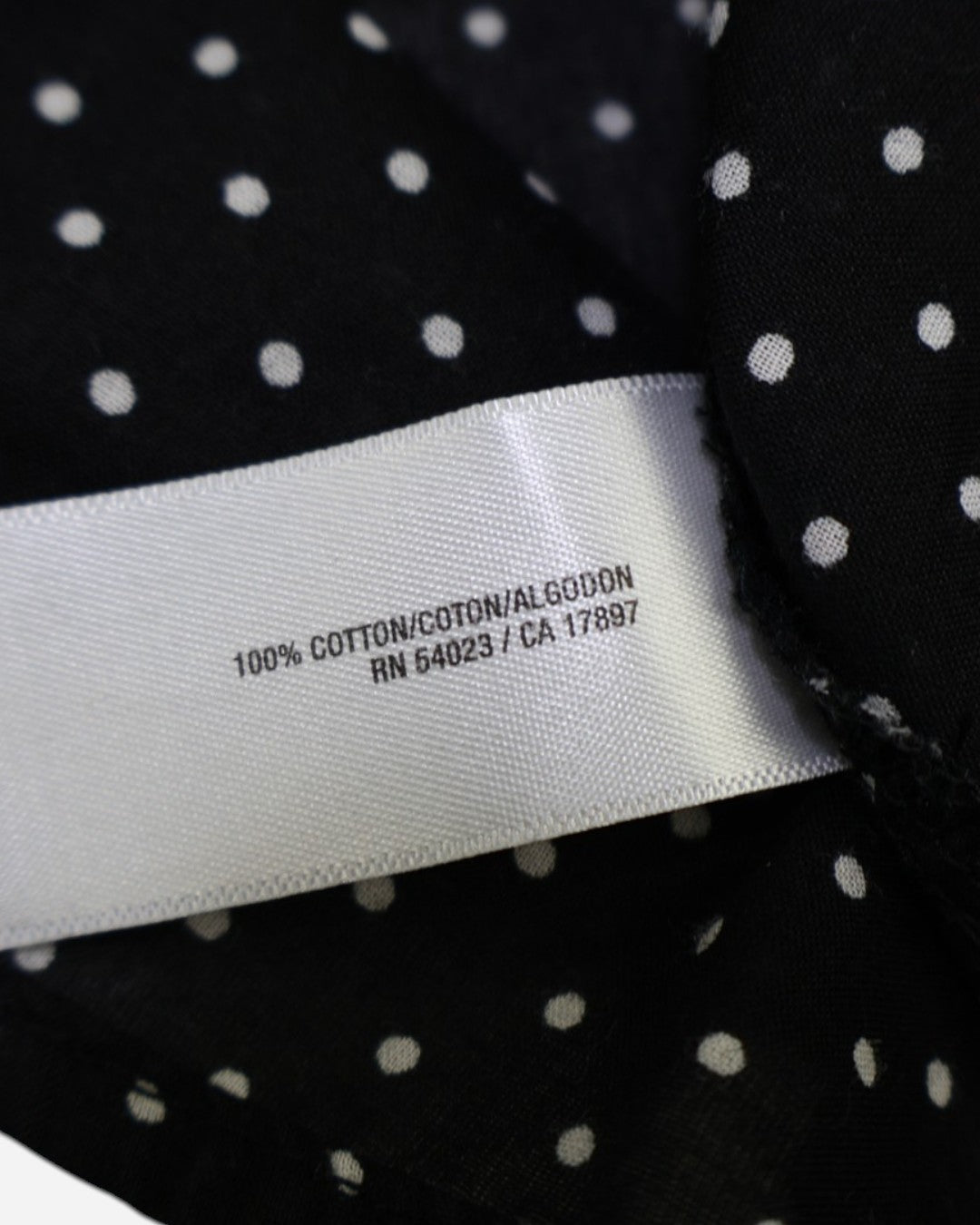 Etiqueta de composición 100% algodón de blusa negra talla XS.