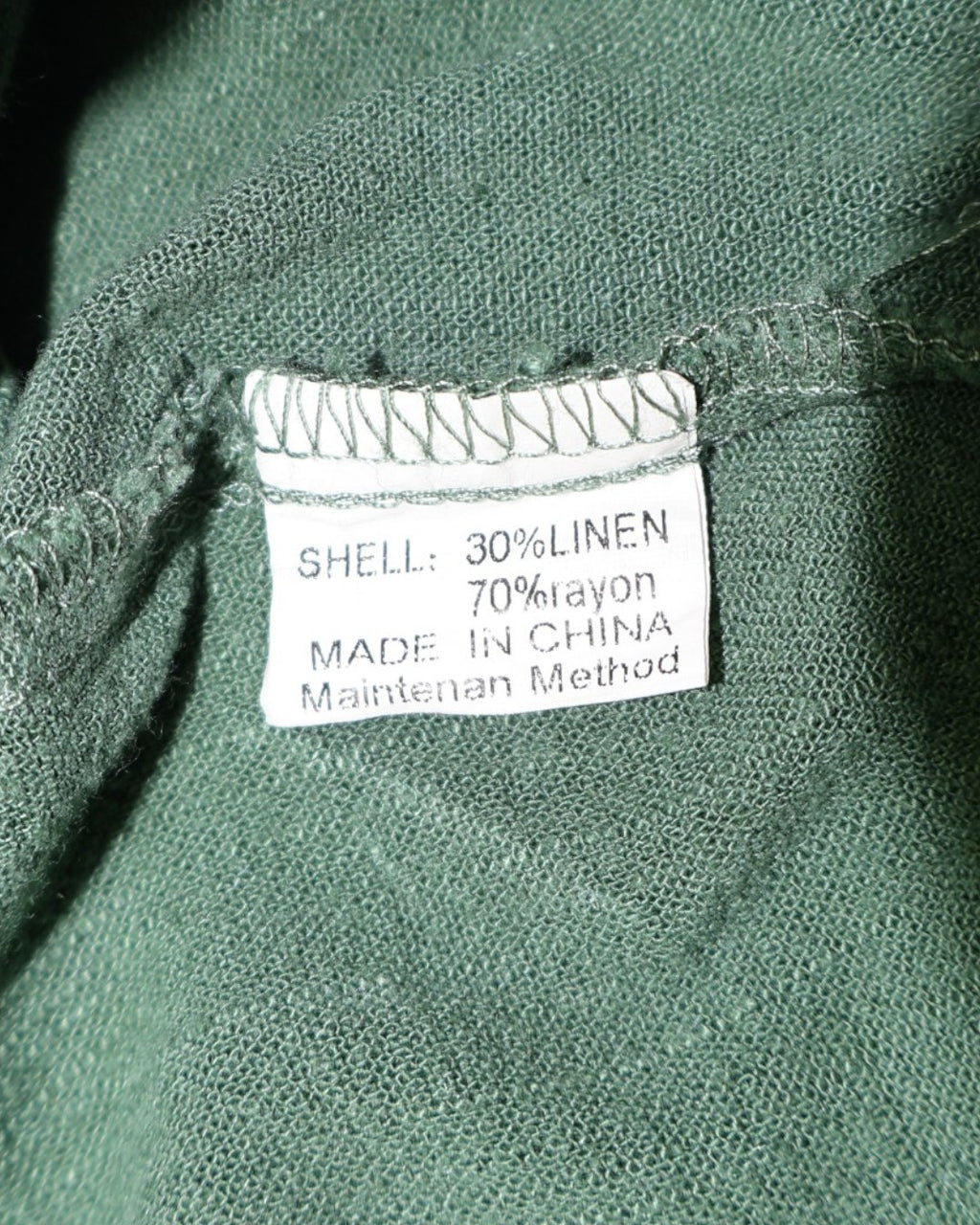 Etiqueta de composición de blusa verde con 70% rayón y 30% lino.