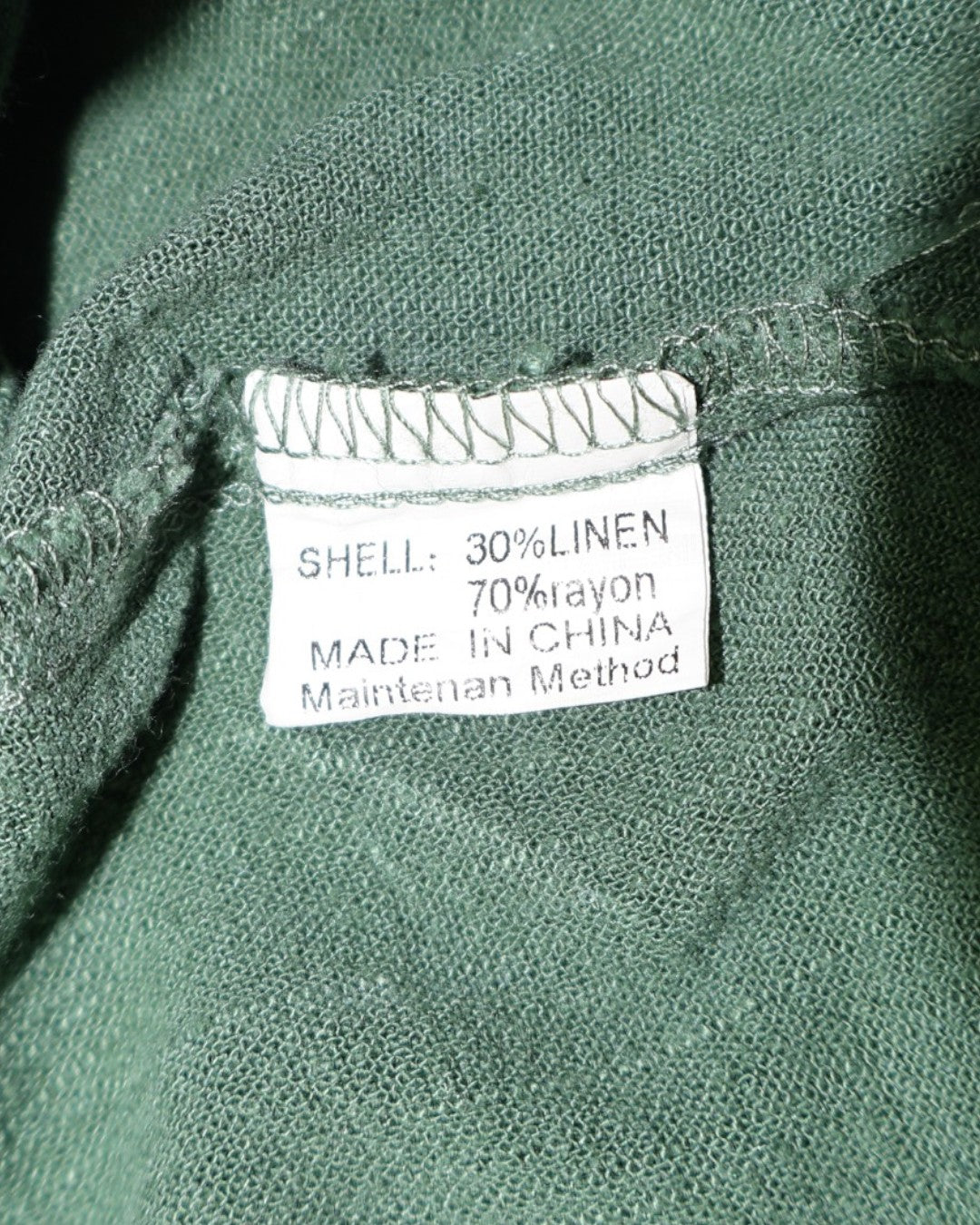 Etiqueta de composición de blusa verde con 70% rayón y 30% lino.