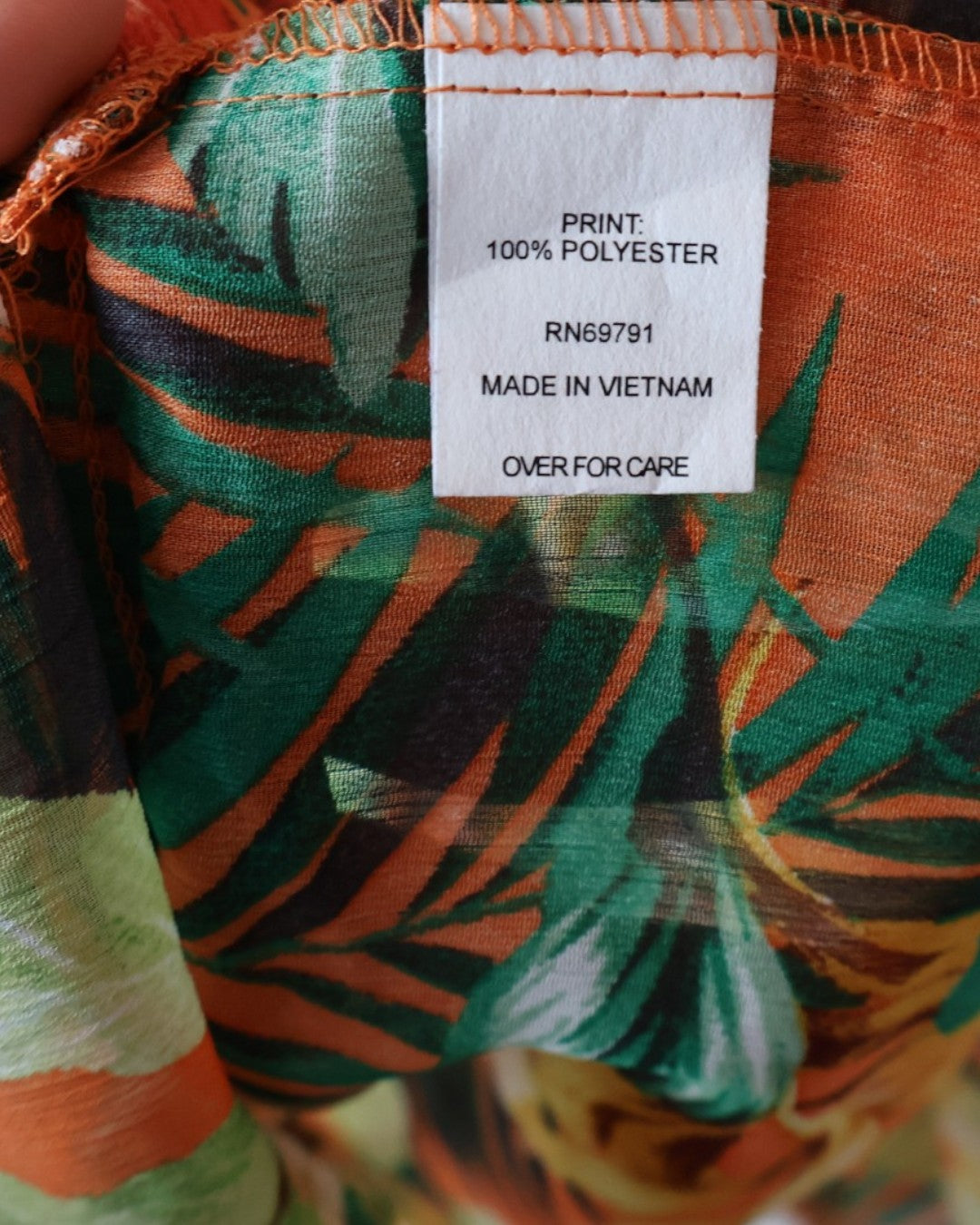 Etiqueta de material 100% poliéster en vestido tropical.