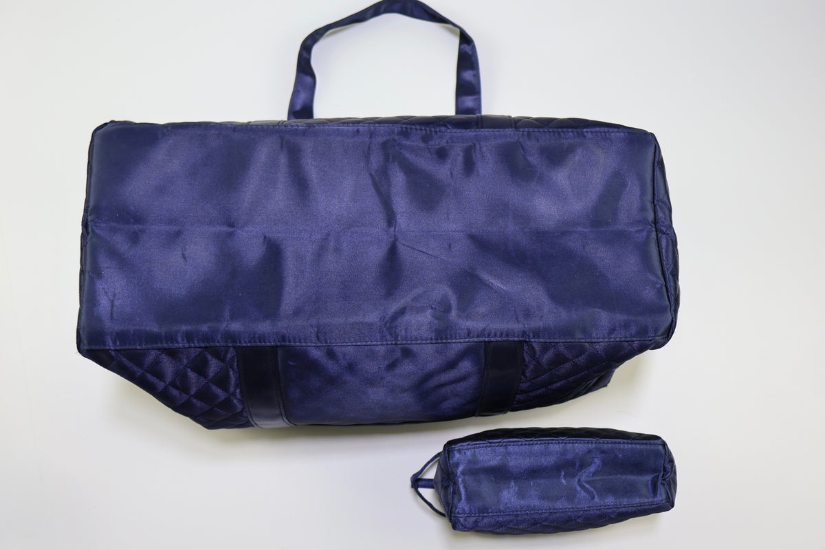 Vista trasera del bolso de viaje acolchado azul marino con bolsillo de zipper.