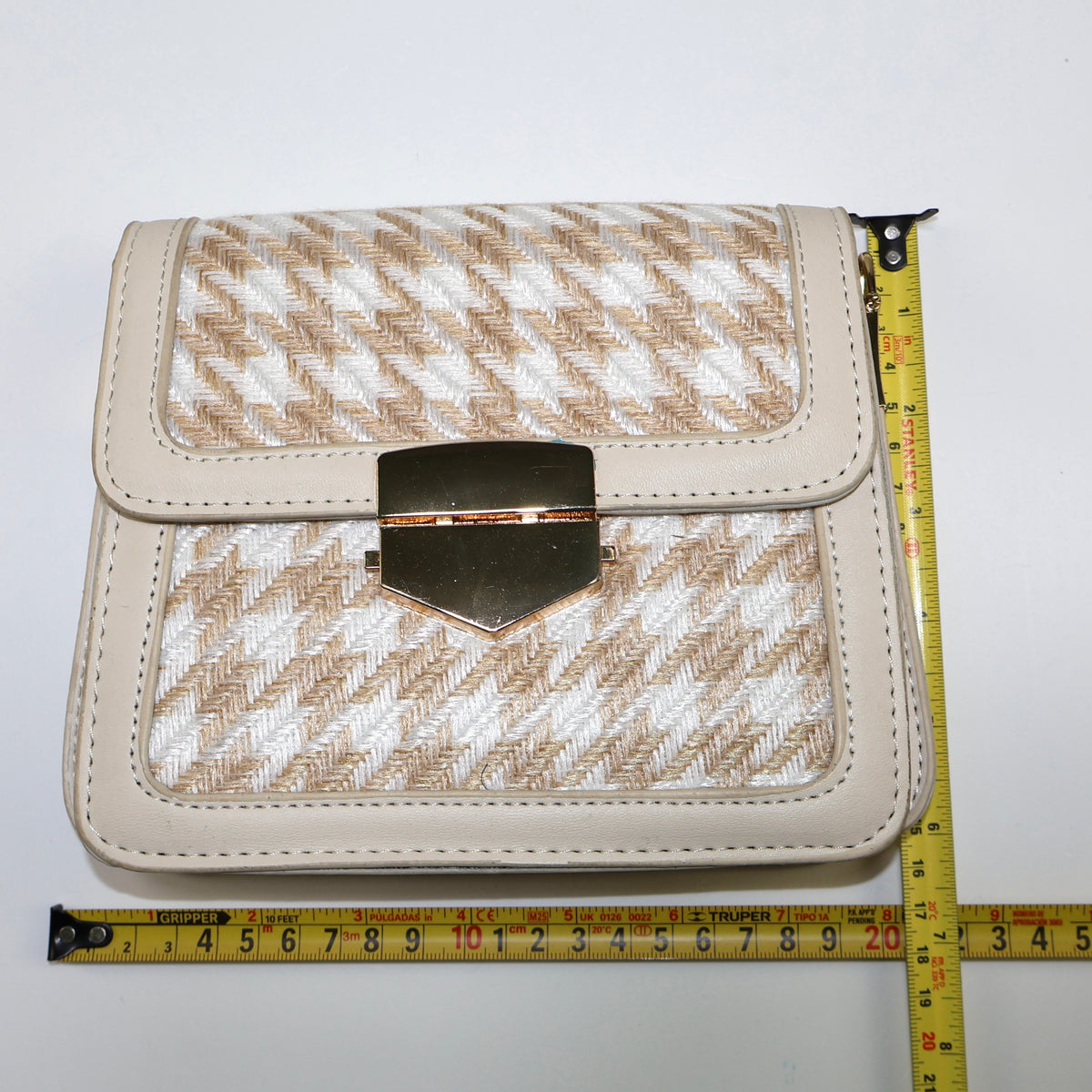 Cartera beige con cinta métrica mostrando sus medidas aproximadas.