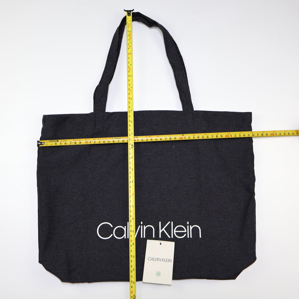 Bolso tote negro Calvin Klein con logo blanco y medidas aproximadas.