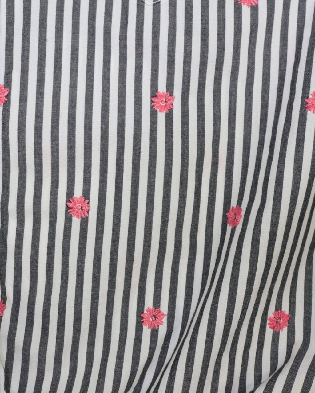 Detalle de flores rosadas bordadas sobre rayas gris y blanco en camisa Gap en The Reset